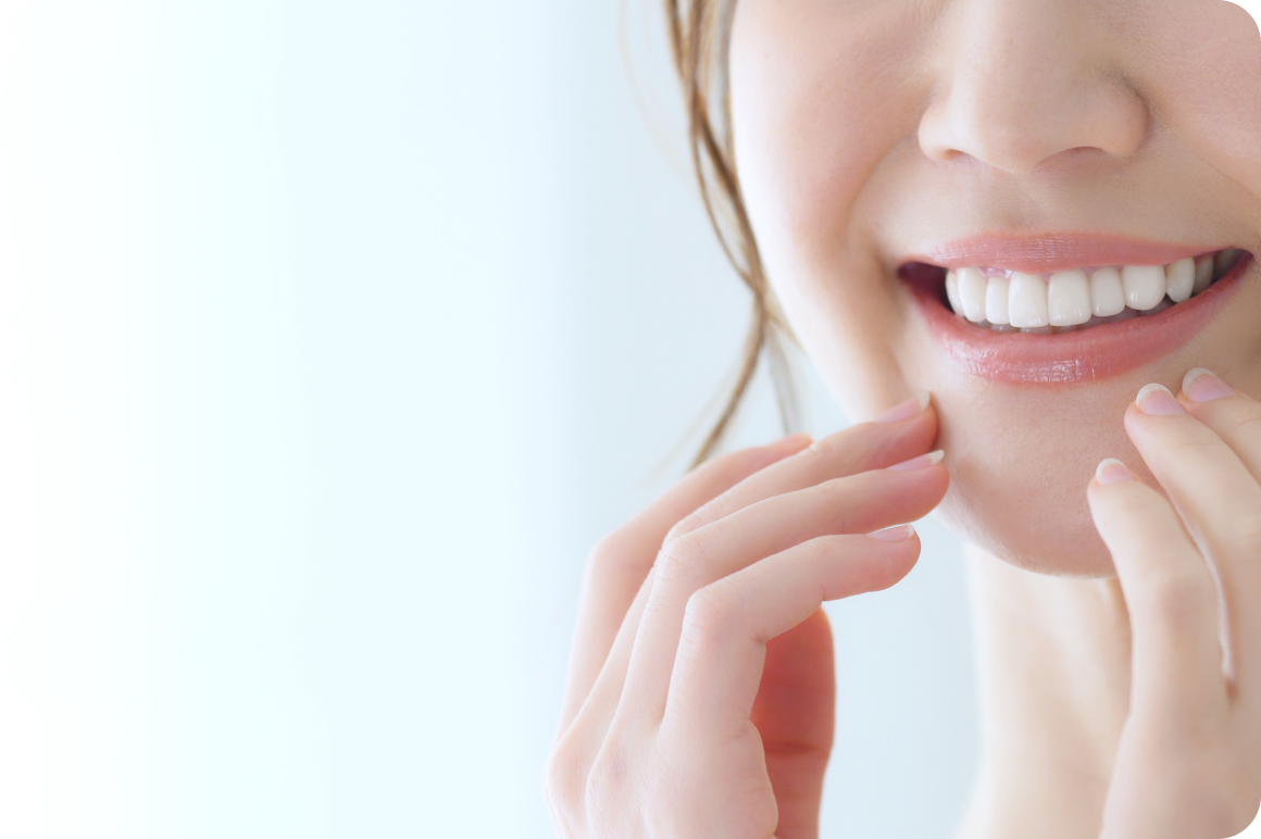 白く整った歯を見せて微笑む女性の口元のアップ