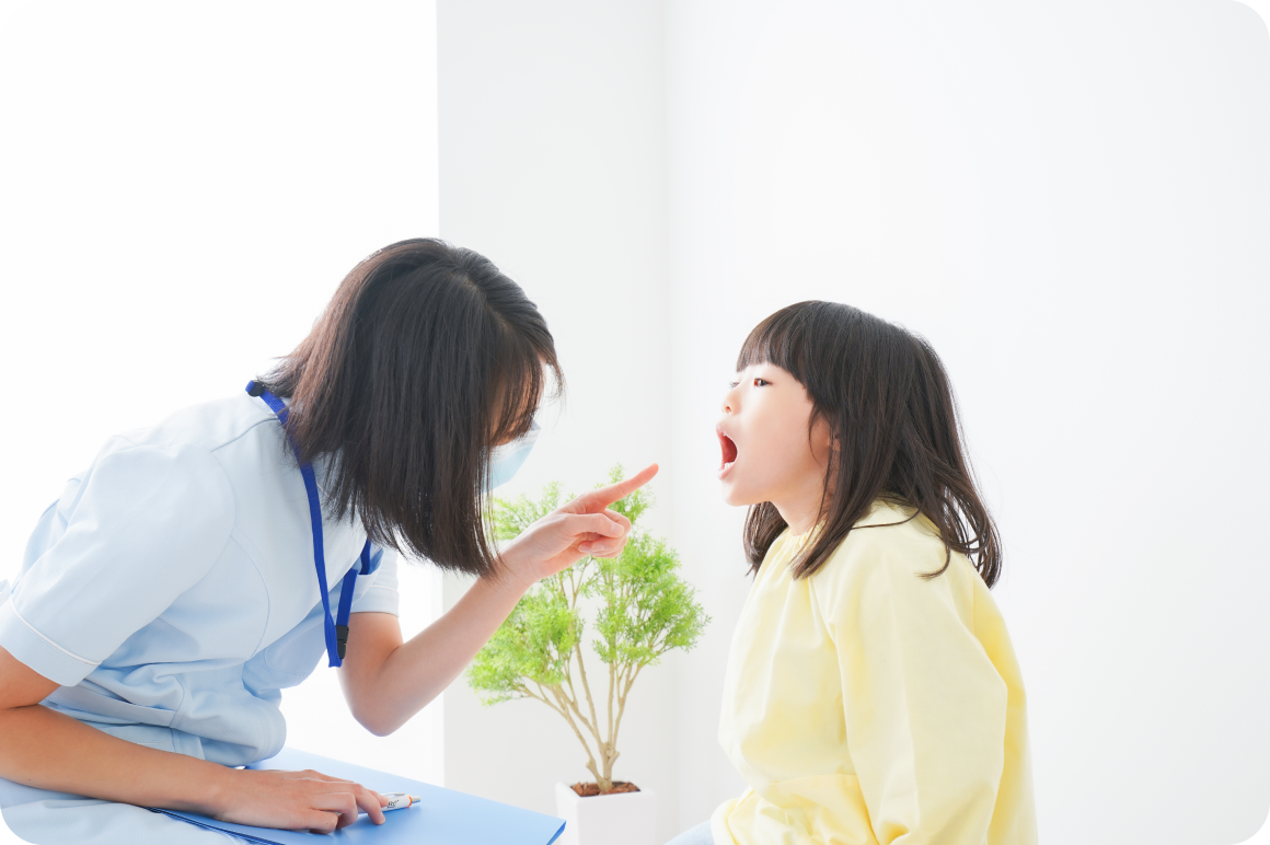 医療従事者が小さな女の子の喉を診察している様子